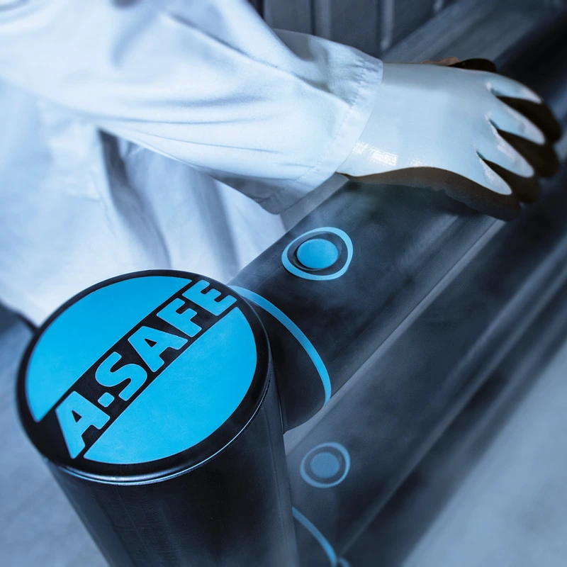 Worker wearing protective clothing and gloves beside an A-SAFE barrier